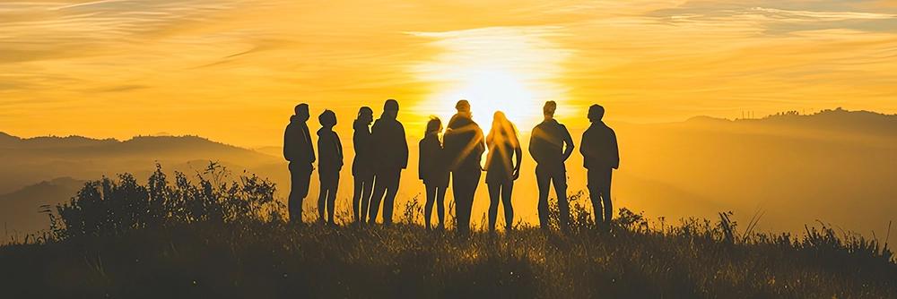 Group of friends watch a sunset together on a hill