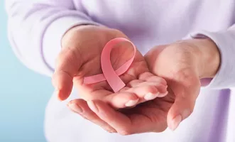 Person holding a pink breast cancer ribbon